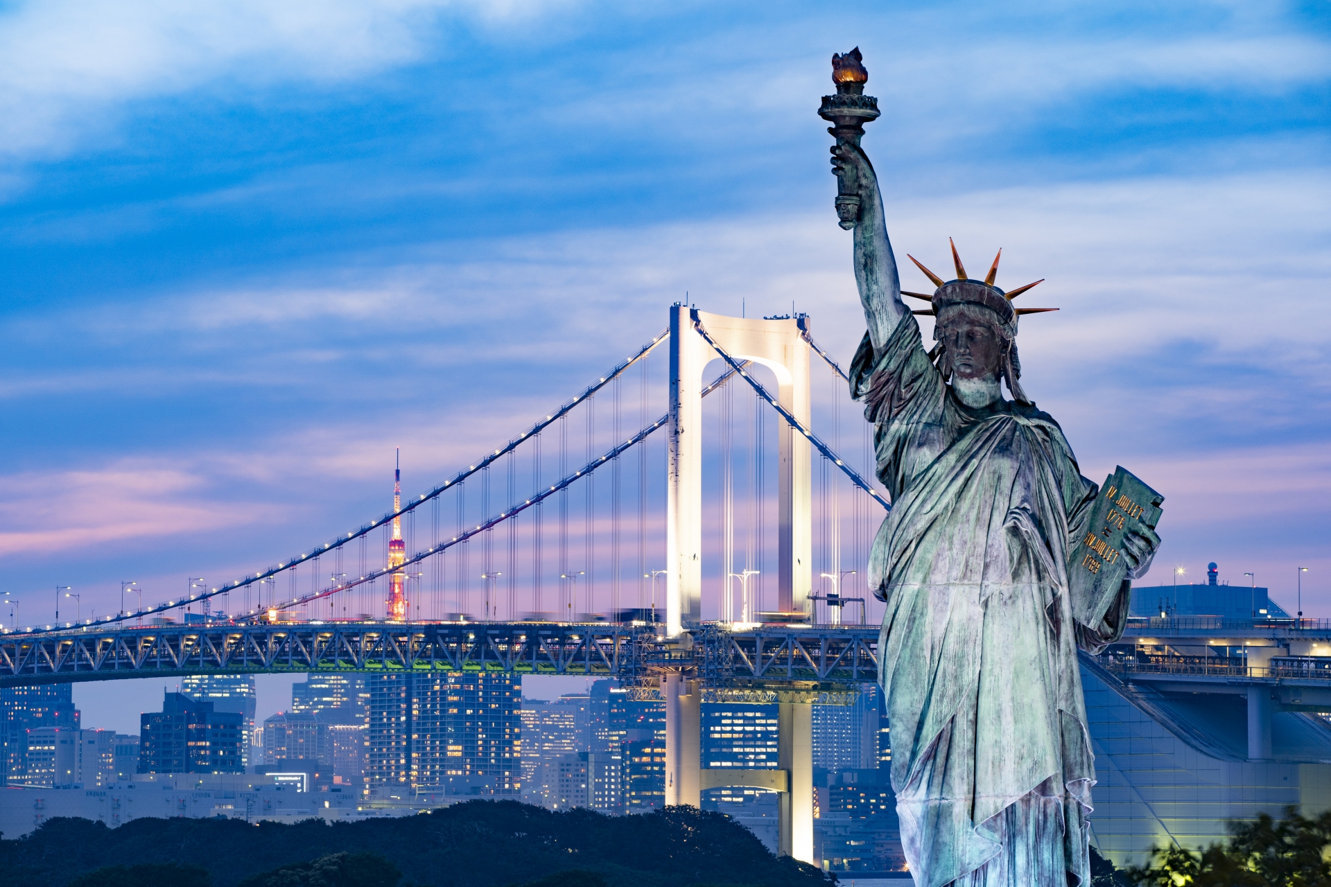 The Statue of Liberty and Rainbow Bridge in Odaiba are lit up at night