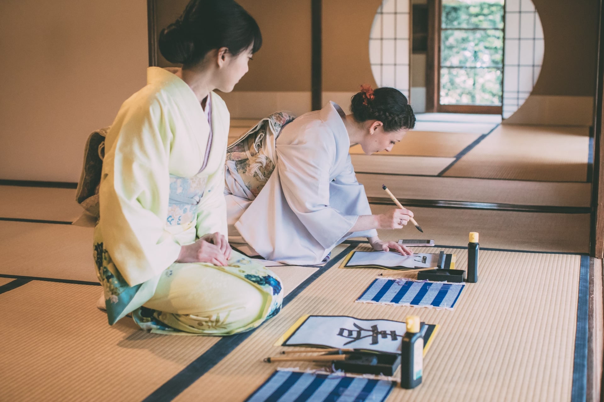 Japanese and foreign girls in kimono doing calligraphy