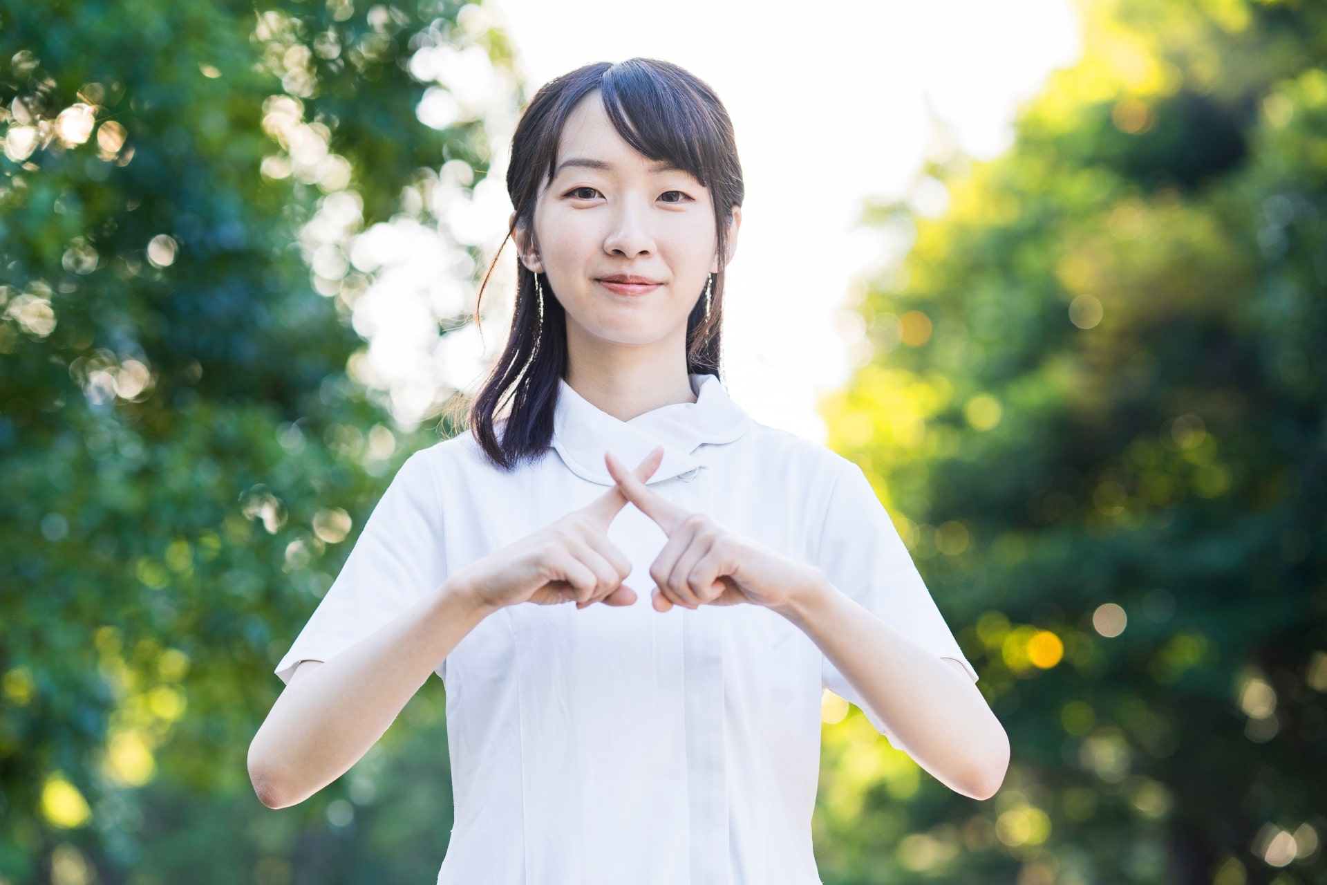 Japanese girl doing a cross sign 